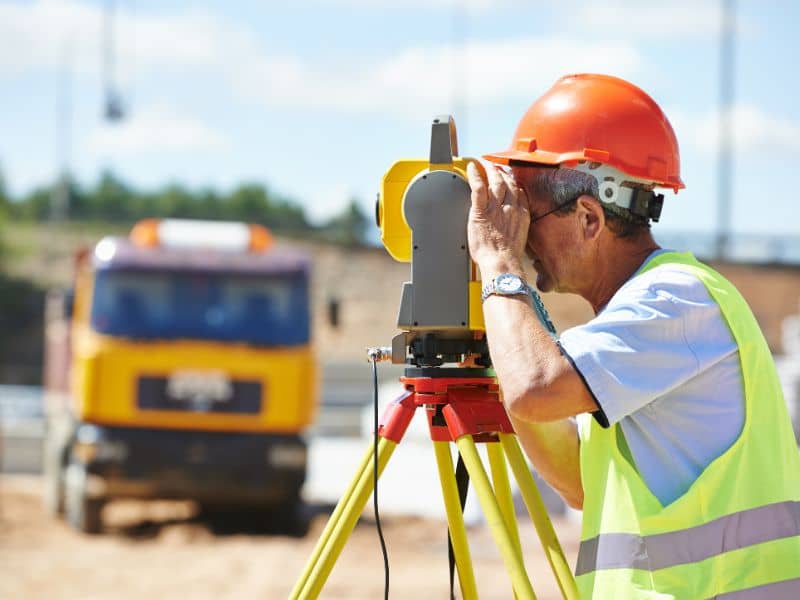 Land surveyor using a total station while performing an ALTA survey for a commercial property development site