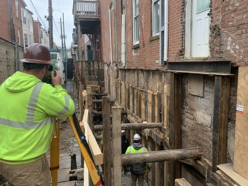 construction survey philadelphia rowhouse excavation - Philadelphia Land Surveying Construction Survey crew checking excavation control beside attached rowhouses in Philadelphia Pennsylvania.